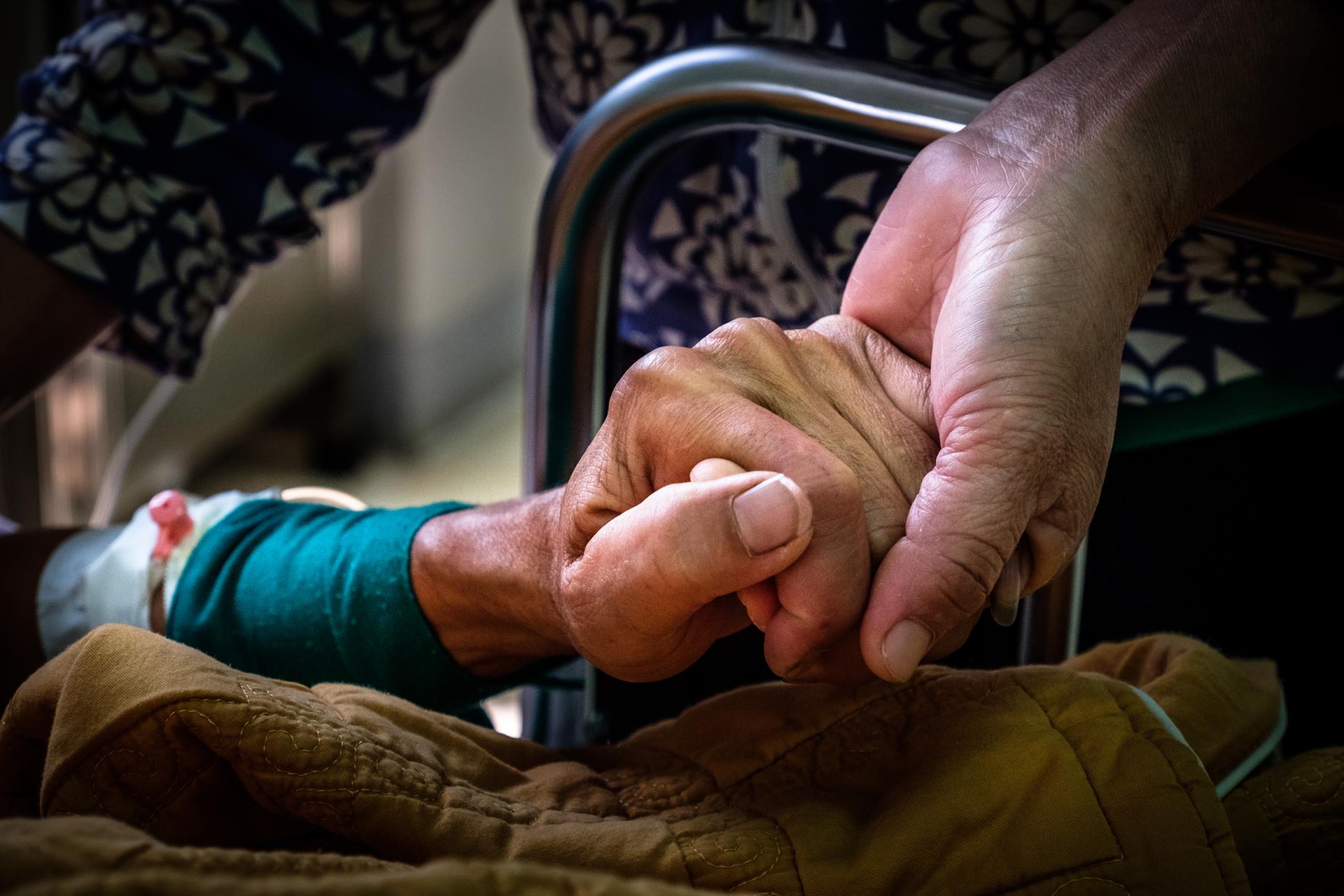 A patient and loved one hold hands.